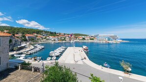A coastal town with a marina, stone buildings, and a modern hotel. - Apartment Ljerka (Postira)