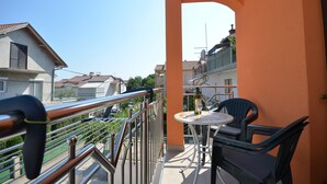 A balcony with a metal railing, a small table with a bottle, and a chair. - Apartments Katarina (Vodice)