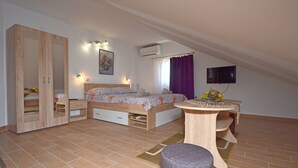 A bedroom with a bed, bedside tables, a wardrobe, a round wooden table, and a television on the wall. - Apartments Katarina (Vodice)