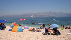 Una playa con tiendas de campaña, sombrillas y gente relajándose.