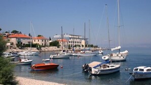 A marina with various boats docked, buildings in the background, and a clear sky. - Apartments Grozdana (Postira)