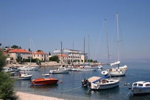A marina with various boats docked, buildings in the background, and a clear sky.