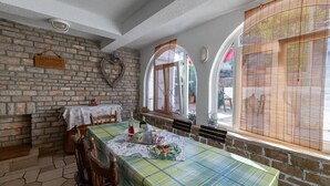 A dining area with a brick wall, a table set with a tablecloth, chairs, and a window with a view. - Apartments Davorka (Gdinj)