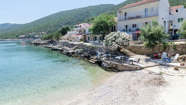 A coastal building with a balcony, a clear view of the sea, and a stone staircase leading down to the beach. - Apartments Davorka (Gdinj)