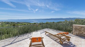A balcony with two sun loungers and a small cart, overlooking a scenic view of the sea and distant mountains. - House Petric (Bol)