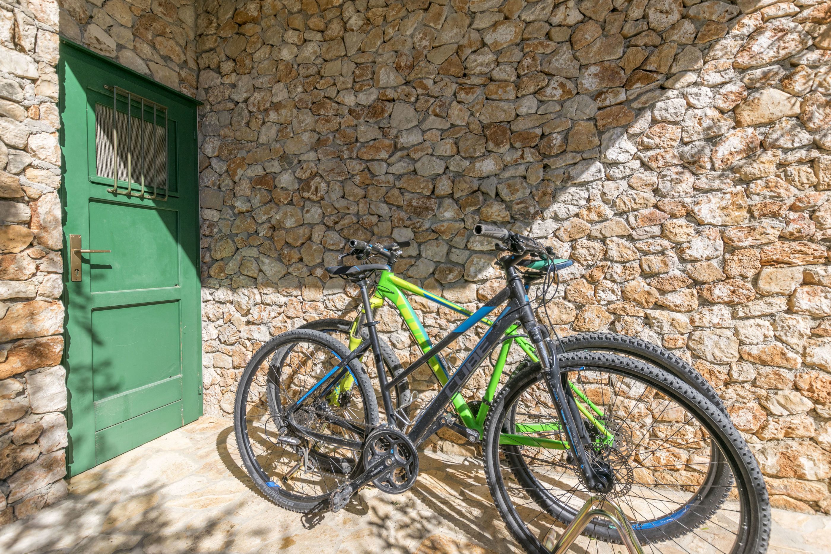 Una bicicleta estacionada junto a un muro de piedra con una puerta verde.