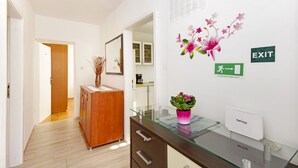 A hotel reception area with a glass desk, a wooden cabinet, a potted plant, and an exit sign. - Apartment Danica (Makarska)