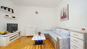 A modern living room with a sofa, TV, and a small table with a flower vase. - Apartment Danica (Makarska)