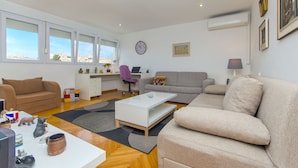 A modern living room with a sofa, a coffee table, and a desk with a computer. - Apartment Sunny (Split)