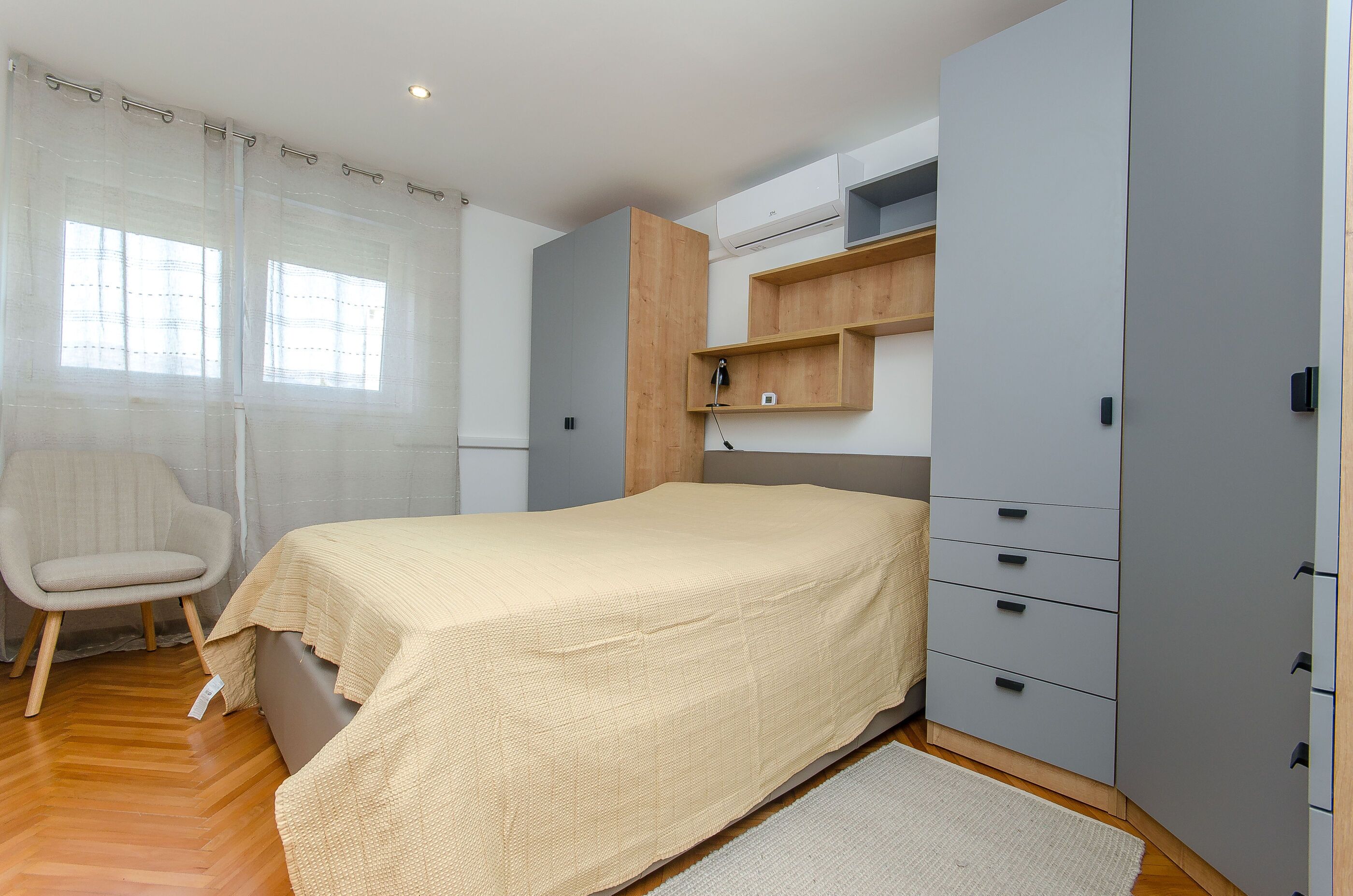 Un dormitorio con cama, una silla, armario y escritorio.