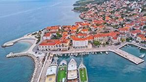 Un pueblo costero con un puerto deportivo, edificios de techos rojos y una vista despejada del mar.