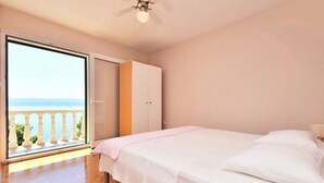 A bedroom with a bed, a wardrobe, and a balcony with a view of the sea. - House Ivan (Mimice)