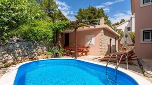 A swimming pool with a stone wall and a wooden deck. - House Ivan (Mimice)