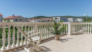 A balcony with a white balustrade, a potted plant, and a white chair. - Apartments Sweet Escape (Vodice)