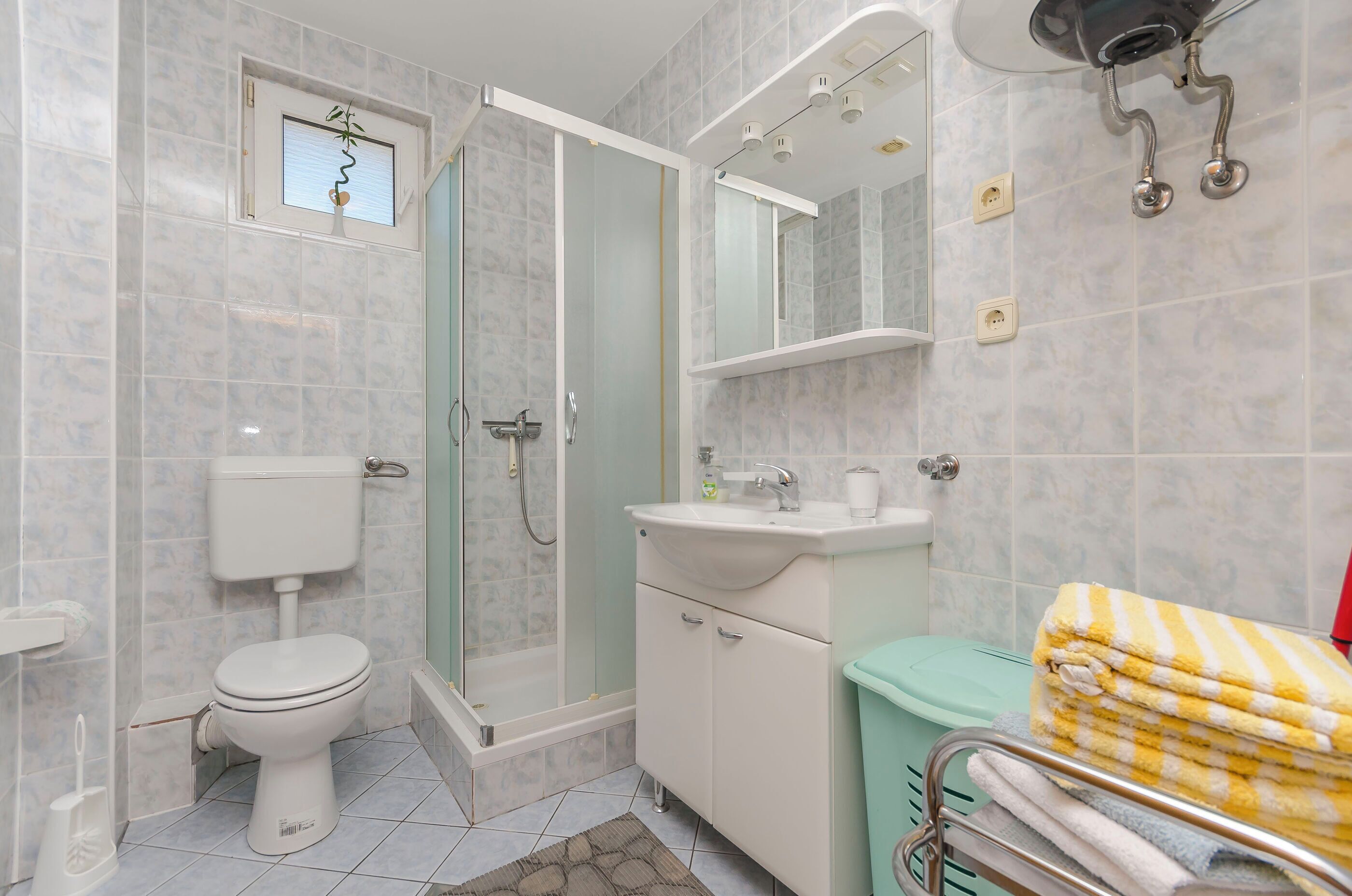 A bathroom with a toilet, shower, sink, and a towel rack.