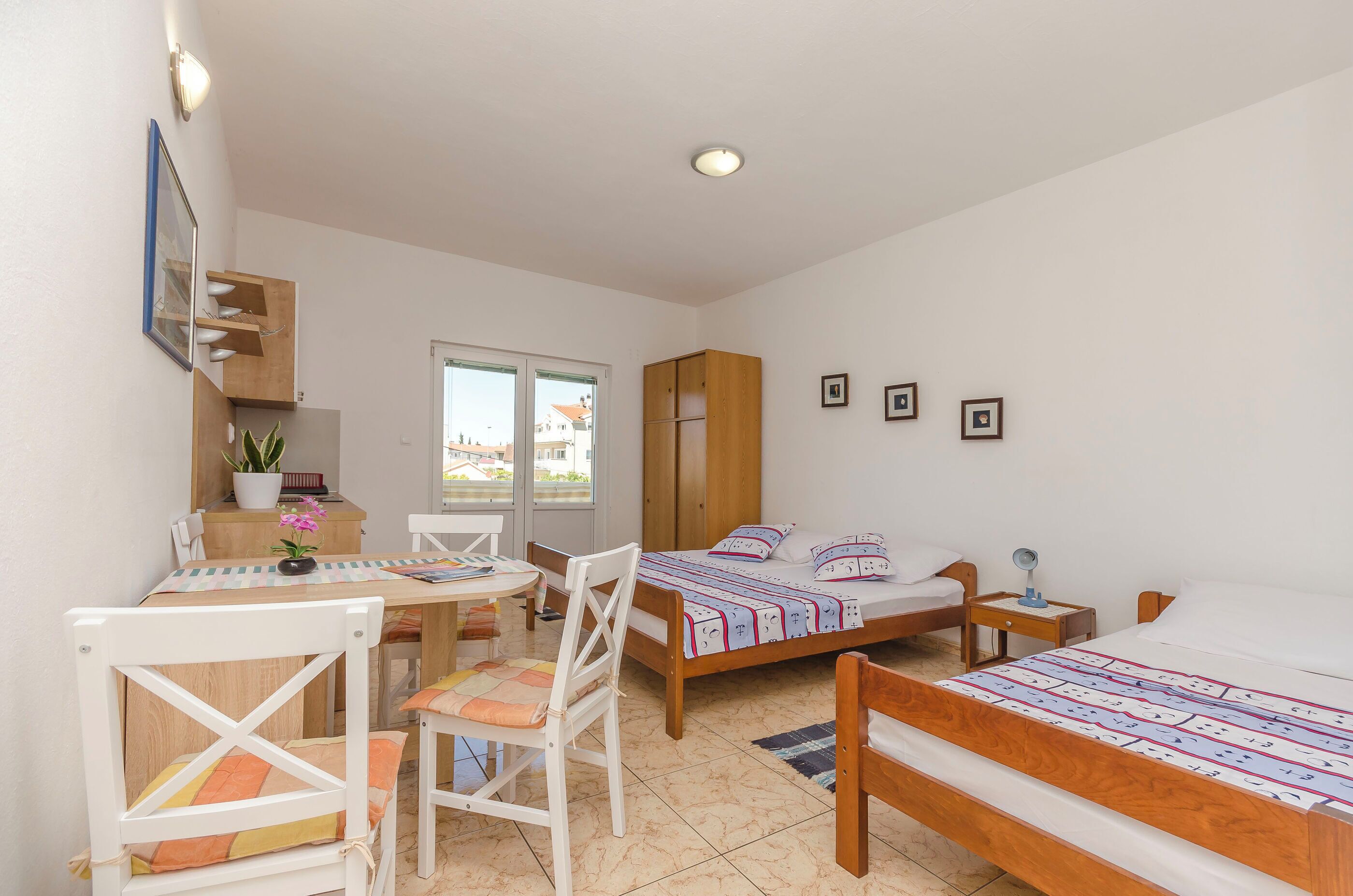 Une chambre avec deux lits, un bureau, des chaises, une petite table et une fenêtre.
