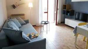 A modern living room with a sofa, a small table with a tray of breakfast items, a TV, and a bookshelf. - Apartment Ivrea center - UNESCO site (Ivrea)
