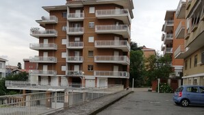 A multi-story residential building with balconies, a parking area, and a fence. - Apartment Ivrea center - UNESCO site (Ivrea)