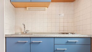 Una cocina con armarios azules, encimera de granito y grifo de acero inoxidable.