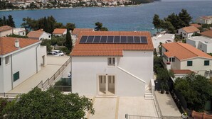 Zona residencial costera con edificios blancos, tejados de tejas rojas y paneles solares en uno de los edificios.