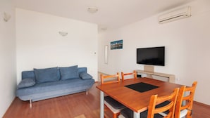 Una sala de estar moderna con un sofá azul, una mesa de comedor de madera y sillas.