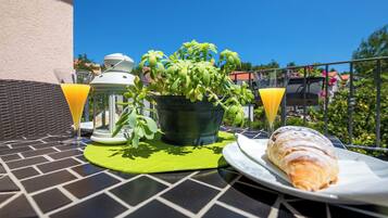 A table with a potted plant, two glasses of orange juice, a lantern, and a plate with a pastry.