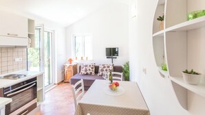 Una cucina compatta con piano cottura, forno e zona pranzo con tavolo apparecchiato per due.