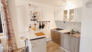 A compact kitchen with a sink, cabinets, a small refrigerator, and a clock on the wall. - Apartments Fran (Vrboska)