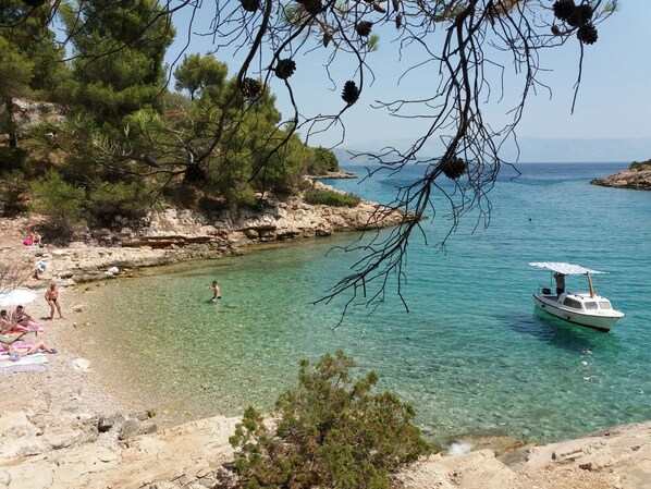 A coastal scene with clear water, a rocky shoreline, and a boat.