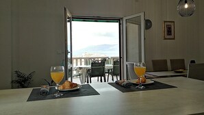 Un coin repas avec une table mise pour le petit-déjeuner, comprenant des croissants et du jus d’orange, et offrant une vue panoramique.