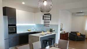 Une cuisine moderne dotée d’un îlot central, d’une table à manger avec des chaises et d’un coin salon avec un canapé.