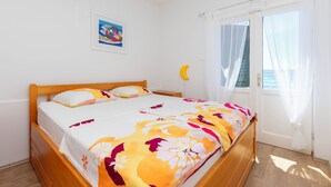 Un lit bien fait, recouvert d’une couvre-lit à motifs floraux, avec une tête de lit en bois et une seule image encadrée accrochée au mur.