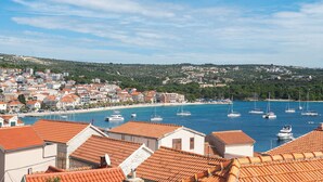 A coastal town with terracotta-roofed buildings, a marina with sailboats, and a beach. - Apartments Zivana (Primosten)