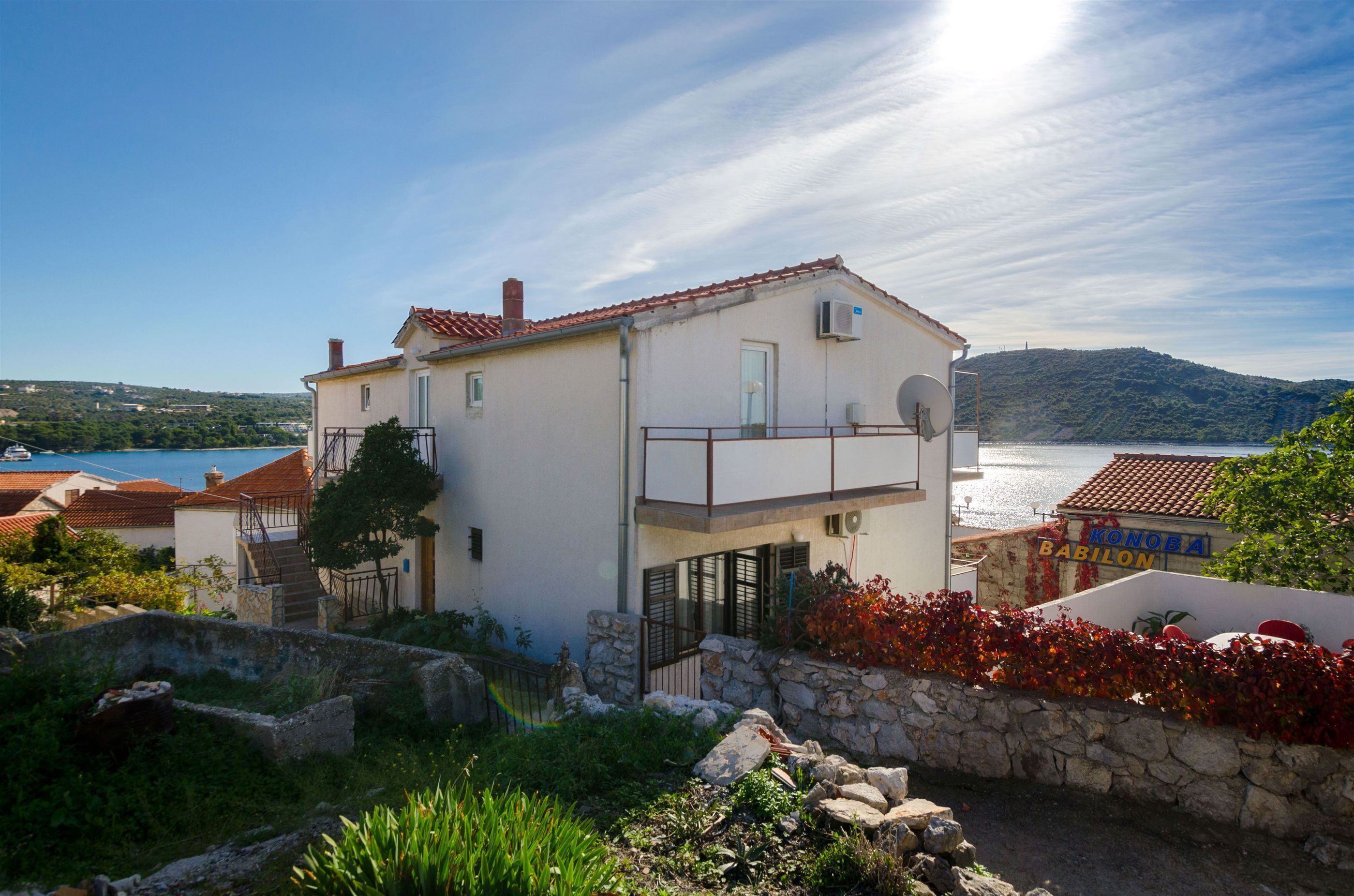 Un bâtiment à deux étages doté d’un balcon, d’un mur en pierre et offrant une vue sur la mer.