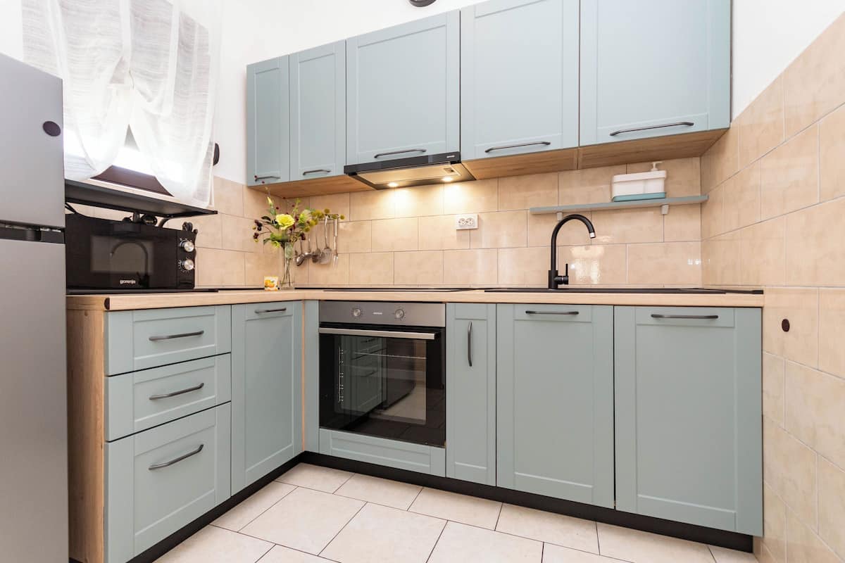 A kitchen with light blue cabinets, a built-in oven, and a sink.