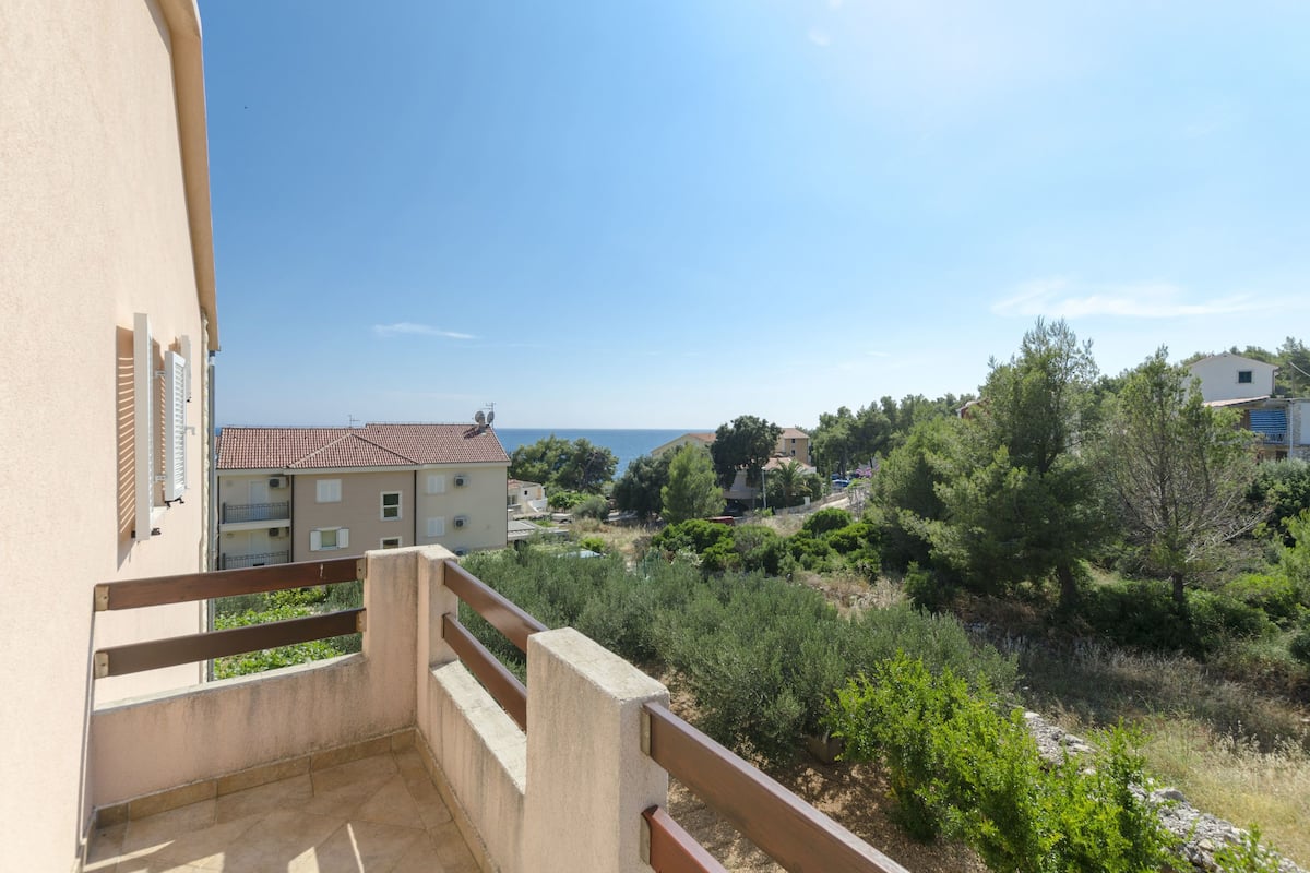 Un balcon donnant sur un quartier résidentiel, avec vue sur des maisons et des arbres.