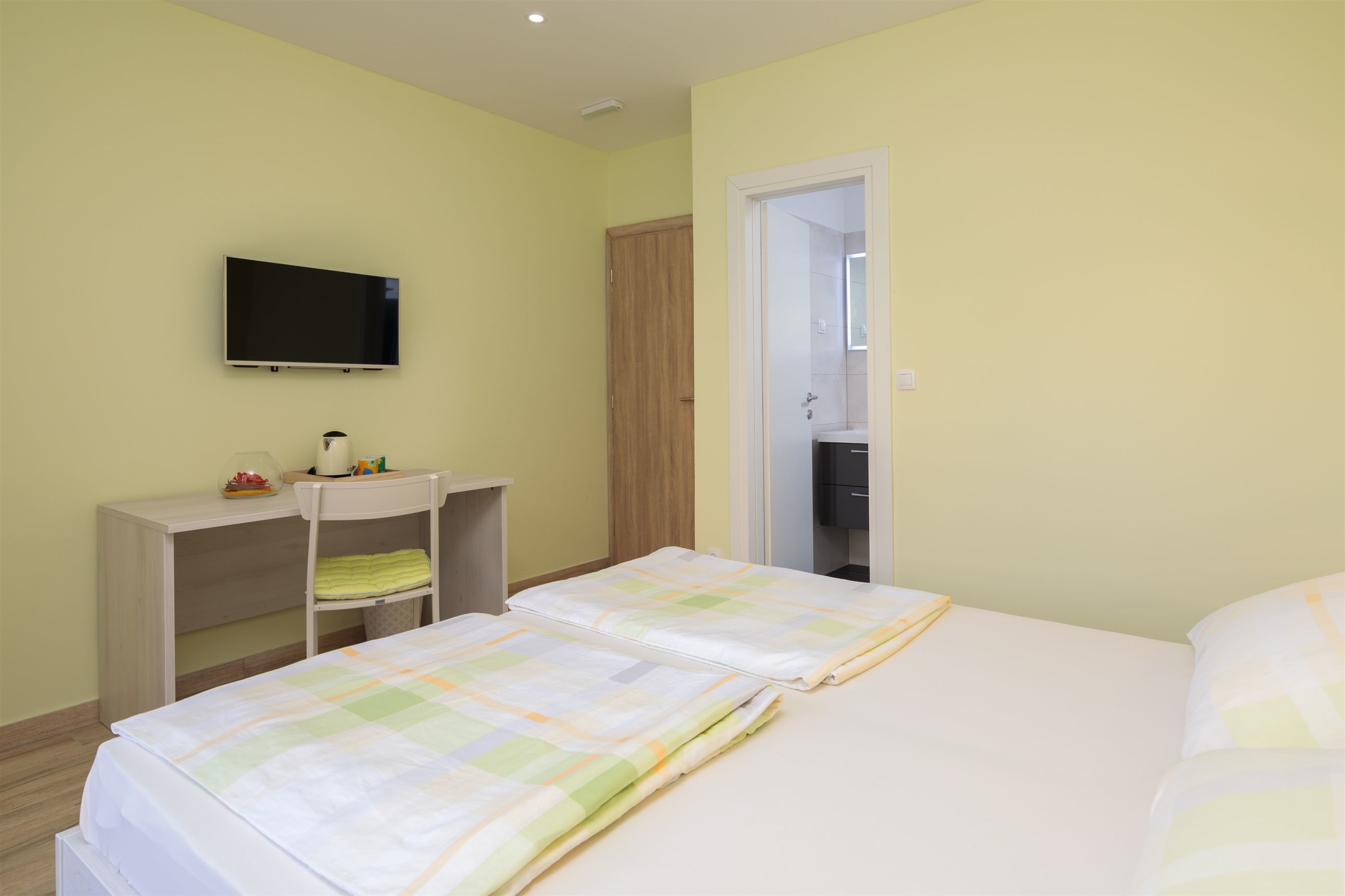 A hotel room with two beds, a TV, a desk, and a wardrobe.