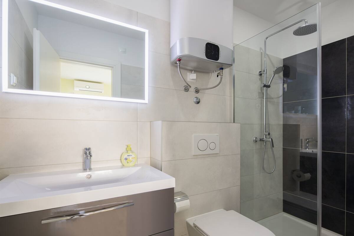 A modern bathroom with a white vanity, a toilet, and a glass-enclosed shower area.