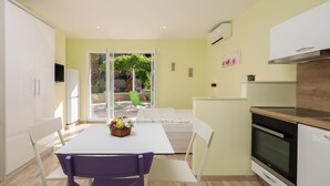 A compact kitchen with a dining area, a sliding glass door to a patio, and a built-in oven. - Apartments and Room Alen (Duce)