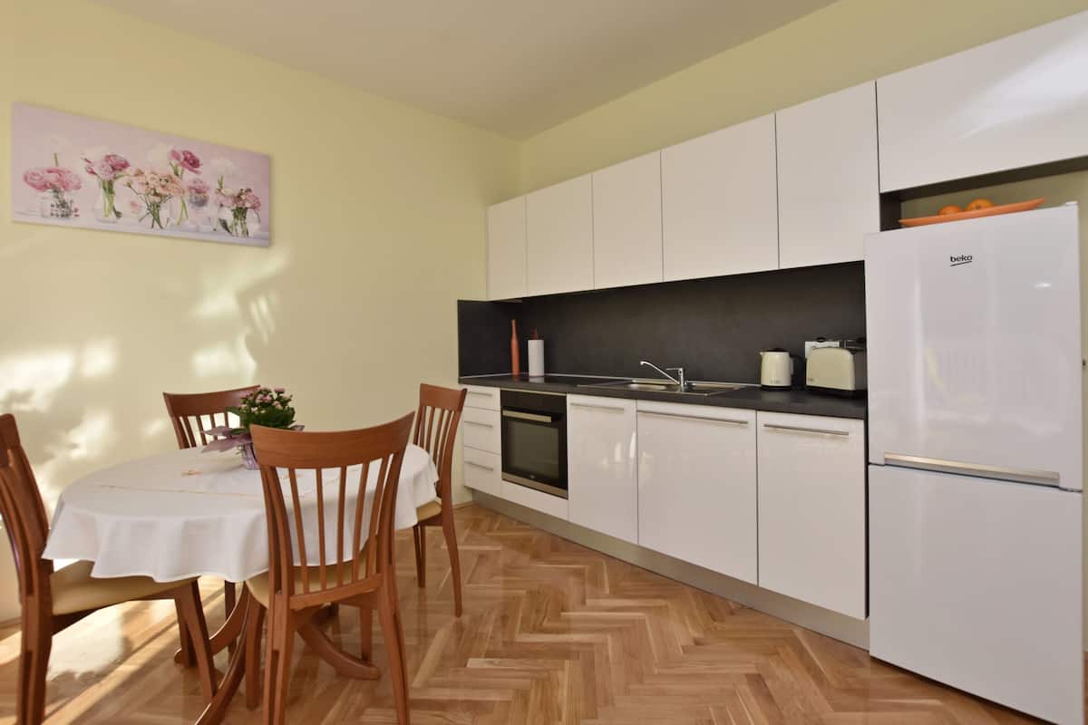 A kitchen with white cabinets, a refrigerator, and a dining table with chairs.