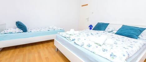 Huoneessa on kaksi sänkyä, joissa on kummassakin kukkakuosiset vuodevaatteet ja siniset tyynyt.