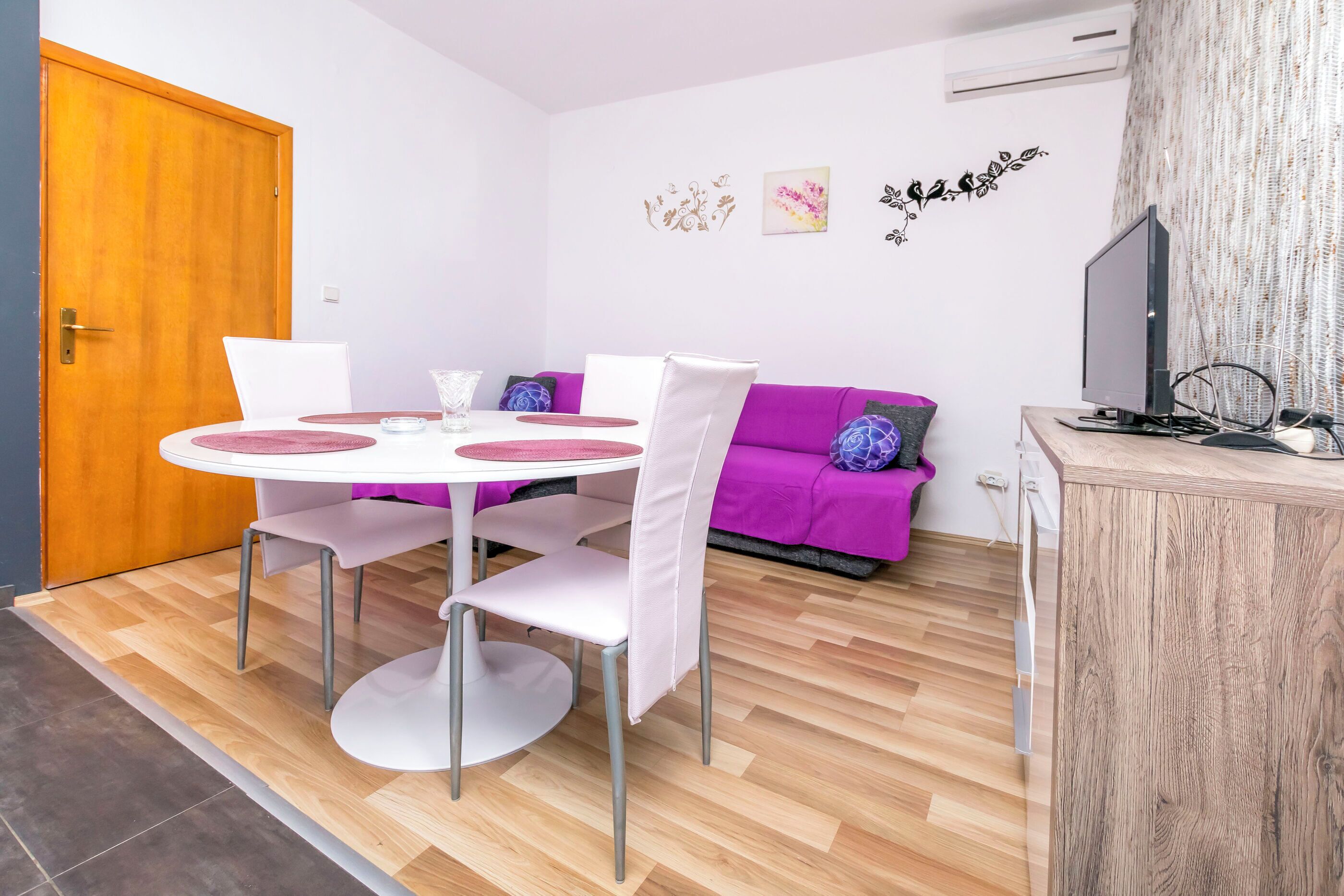 Un espace de vie compact comprenant une table à manger, des chaises, un canapé et un téléviseur.
