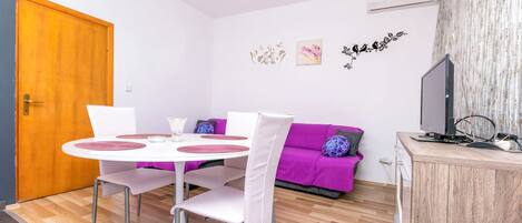 Un espace de vie compact comprenant une table à manger, des chaises, un canapé et un téléviseur.