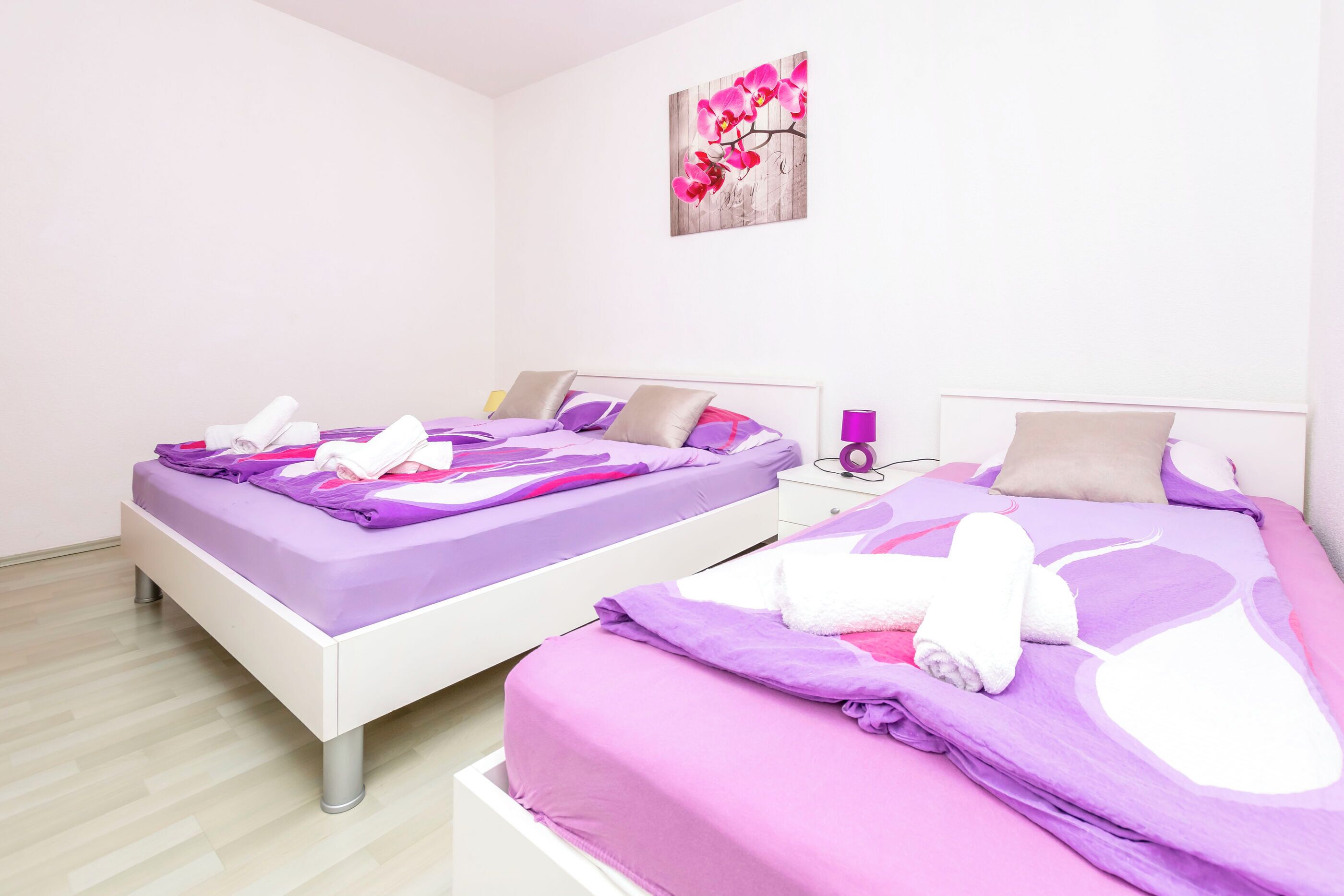 Une chambre avec deux lits, chacun étant agrémenté de draps violets et de serviettes blanches.
