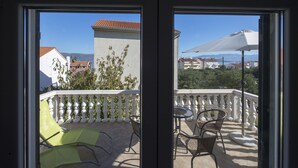 Un balcone con ringhiera bianca, un tavolo e due sedie.
