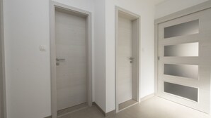 Un corridoio con tre porte, una con maniglia e due con pannelli di vetro.