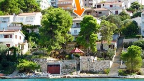A coastal town with buildings, a red umbrella, and a staircase leading to a higher area. - Apartment Jakov (Okrug Donji)