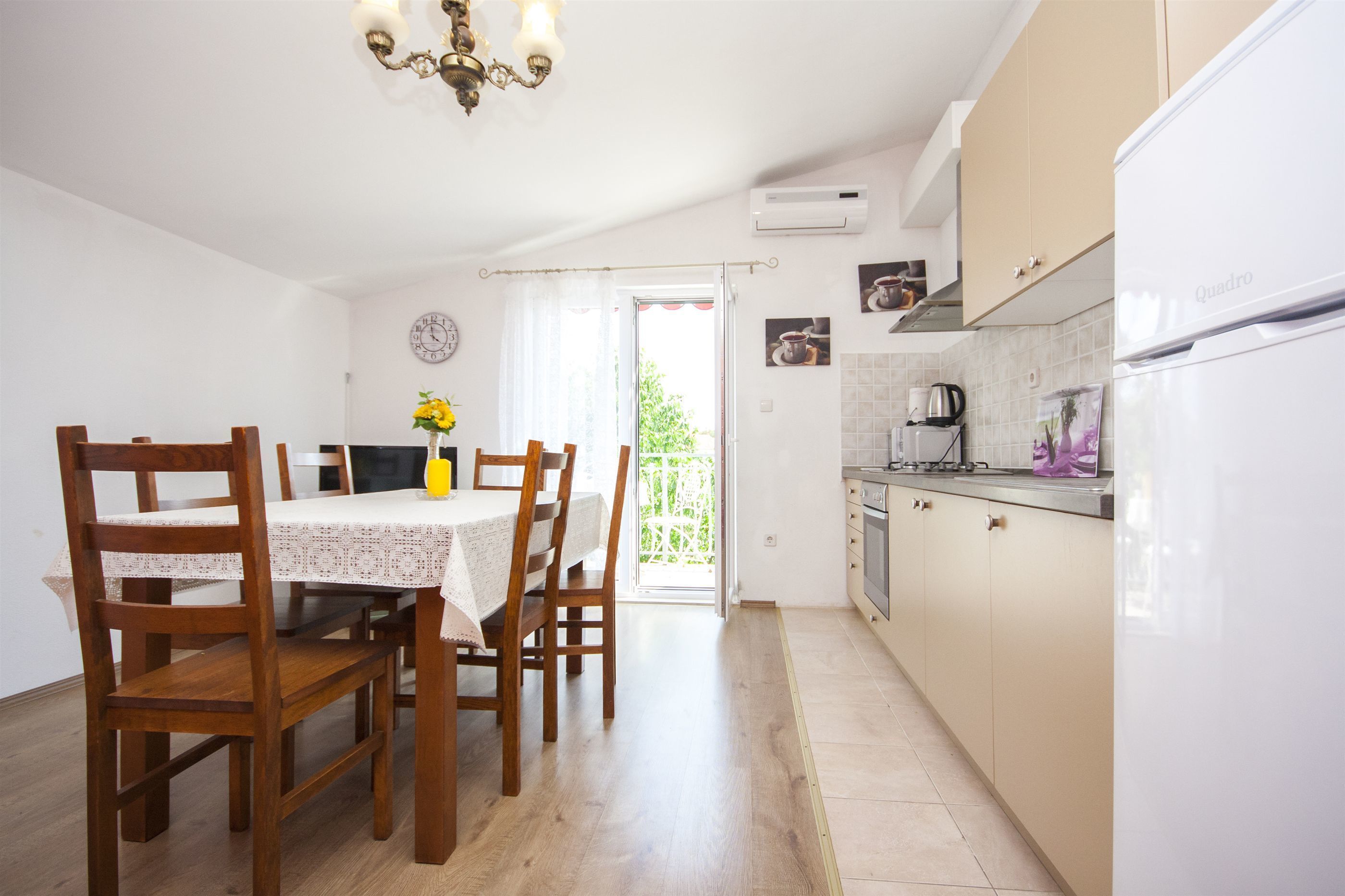 A kitchen with a dining table, chairs, and a refrigerator.