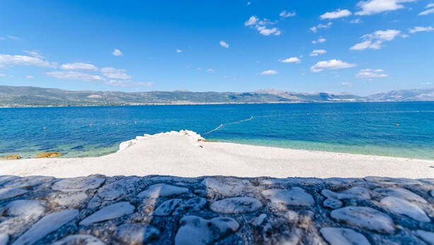 Una spiaggia con acque cristalline e un sentiero di pietra che conduce alla riva.