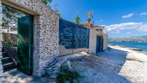 Edificio costiero con facciata in pietra, una porta verde e un cancello in metallo.
